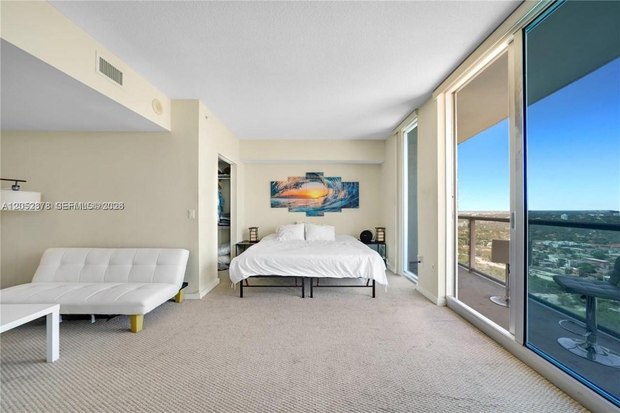 A bedroom features a bed, a white sofa, and a balcony with a city view — 185 SW 7th St # 3100, Miami FL 33130, MIAMI, FL