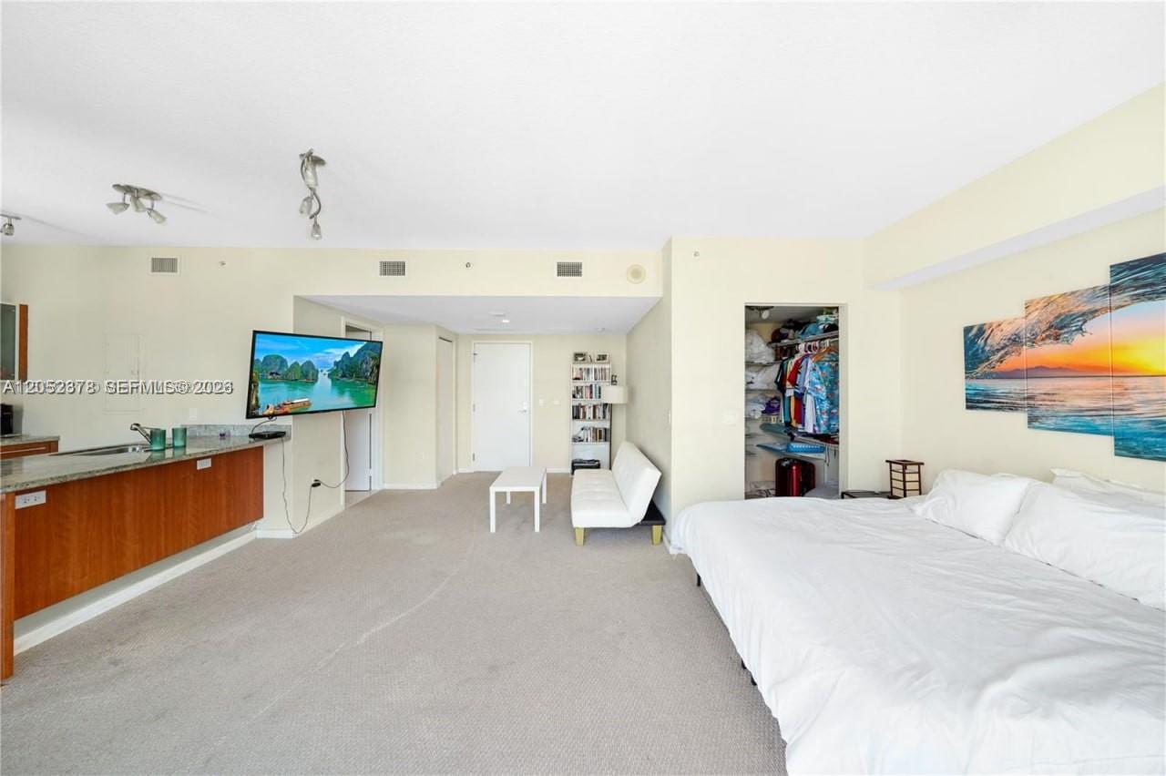 A studio apartment features a bed, a small sofa, a television, and a kitchen counter — 185 SW 7th St # 3100, Miami FL 33130, MIAMI, FL
