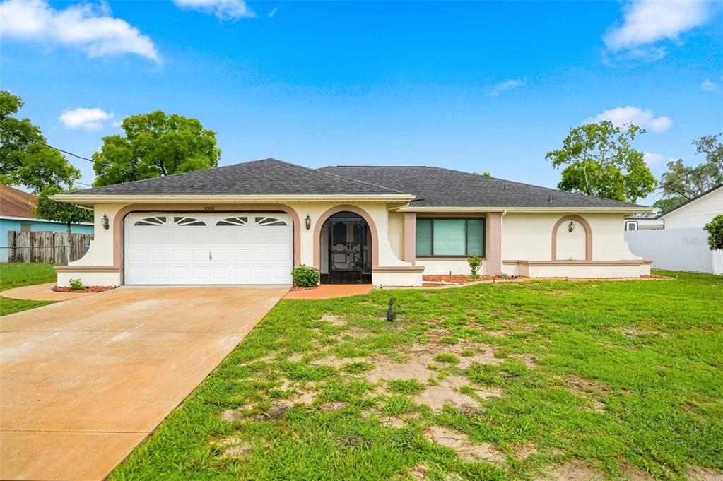 A single-story house with a white garage, arched entryway, and a large front lawn — 10308 GIFFORD DRIVE, SPRING HILL, FL
