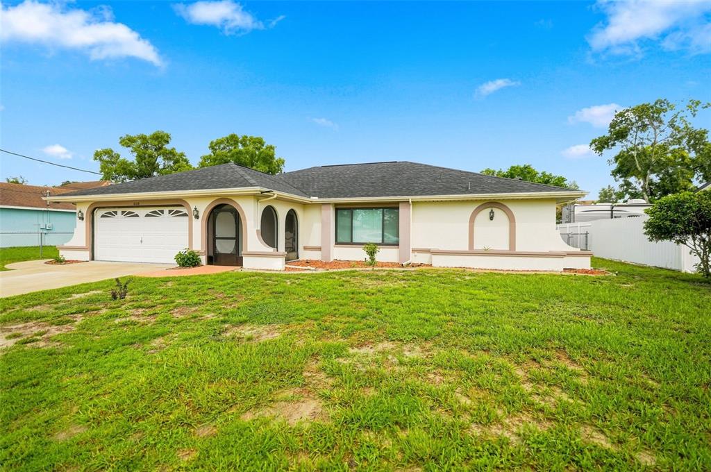 A single-story house with a white stucco exterior, a two-car garage, and a front lawn — 10308 GIFFORD DRIVE, SPRING HILL, FL