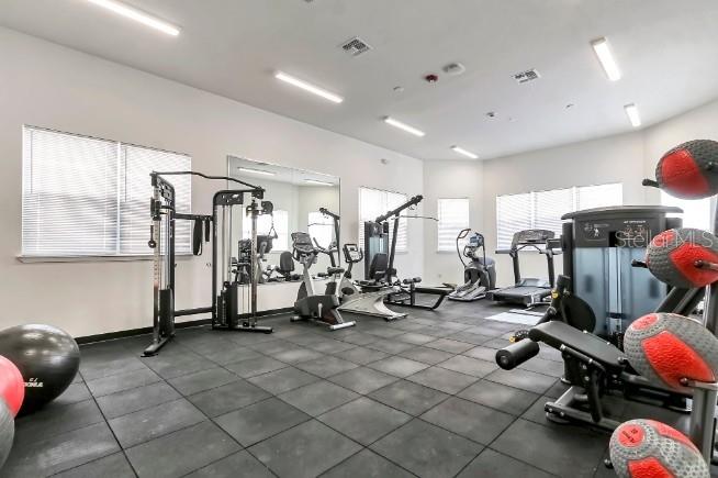 A gym with rubber flooring, various exercise machines, and large windows with blinds — 1230 SOUTHSTATION PLACE UNIT 104, ORLANDO, FL