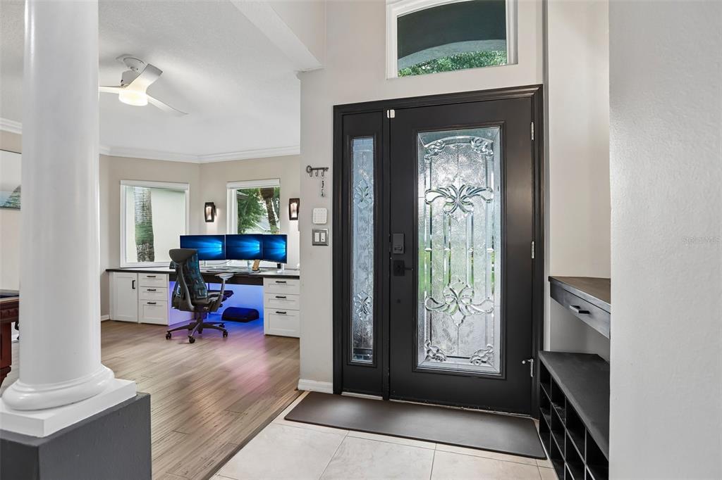 An entryway with a dark glass-paneled front door leads to a home office with three monitors — 19009 FALCONS PLACE, TAMPA, FL