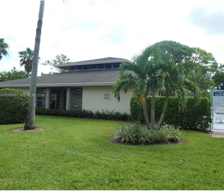 A single-story building with a hip roof and clerestory windows sits behind a grassy lawn — 1798 Abbey Rd # 107, West Palm Beach FL 33415, WEST PALM BEACH, FL