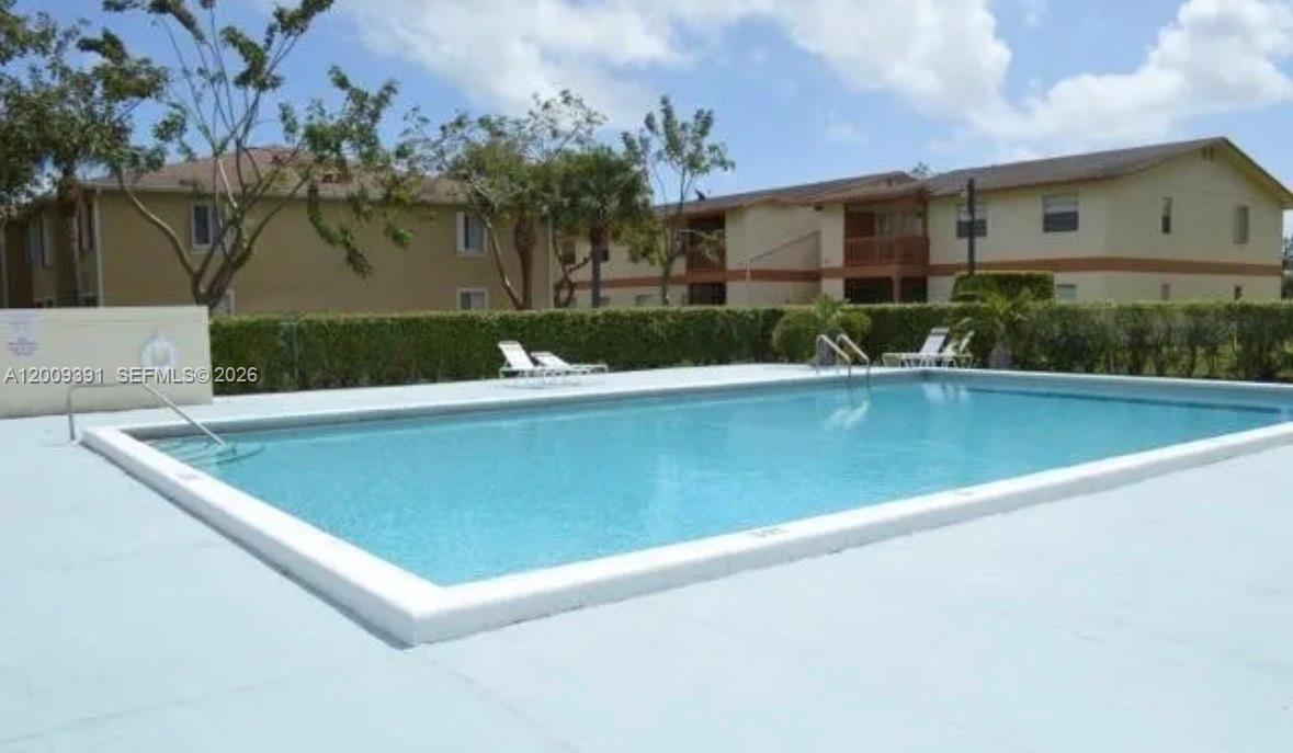 A rectangular swimming pool sits in front of a two-story apartment building — 1798 Abbey Rd # 107, West Palm Beach FL 33415, WEST PALM BEACH, FL
