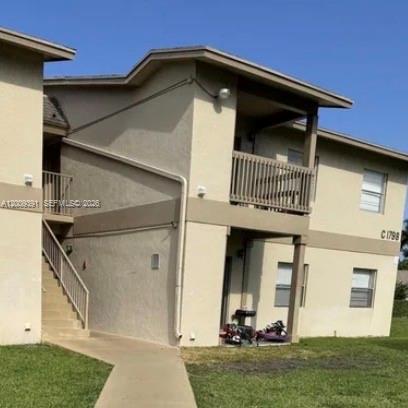A two-story tan apartment building features an exterior staircase and a second-floor balcony — 1798 Abbey Rd # 107, West Palm Beach FL 33415, WEST PALM BEACH, FL