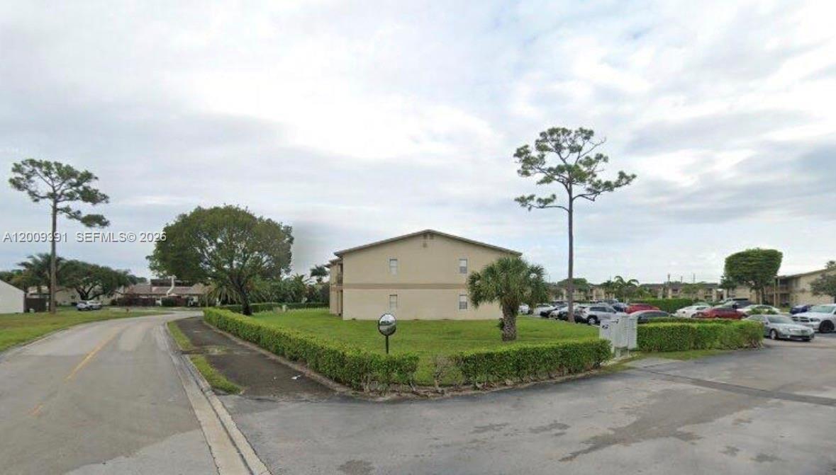 A two-story apartment building sits on a grassy lot next to a paved road — 1798 Abbey Rd # 107, West Palm Beach FL 33415, WEST PALM BEACH, FL