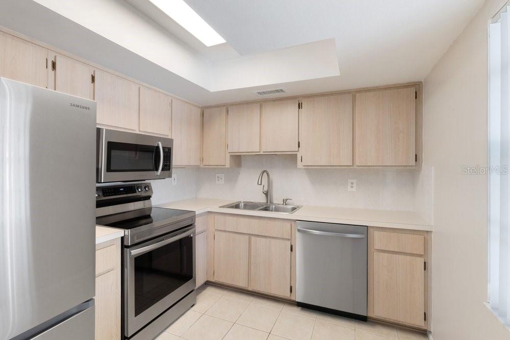A kitchen with light wood cabinets, stainless steel appliances, and a double sink — 9224 KEYES PLACE, NEW PORT RICHEY, FL