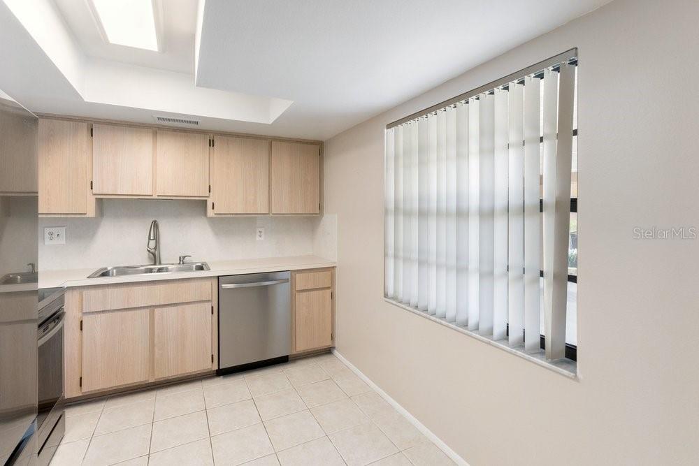 A kitchen with light wood cabinets, stainless steel appliances, and vertical blinds over a window — 9224 KEYES PLACE, NEW PORT RICHEY, FL