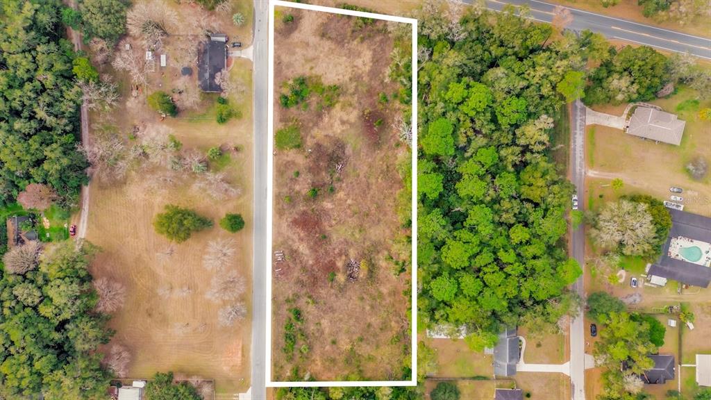 An aerial view shows a rectangular vacant lot outlined in white between two paved roads — 3653 NE JACKSONVILLE ROAD, OCALA, FL