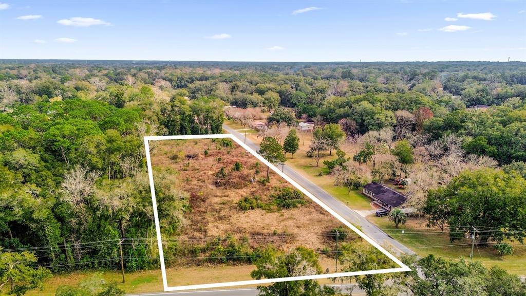 An aerial view shows a rectangular, undeveloped lot bordered by a road and dense trees — 3653 NE JACKSONVILLE ROAD, OCALA, FL