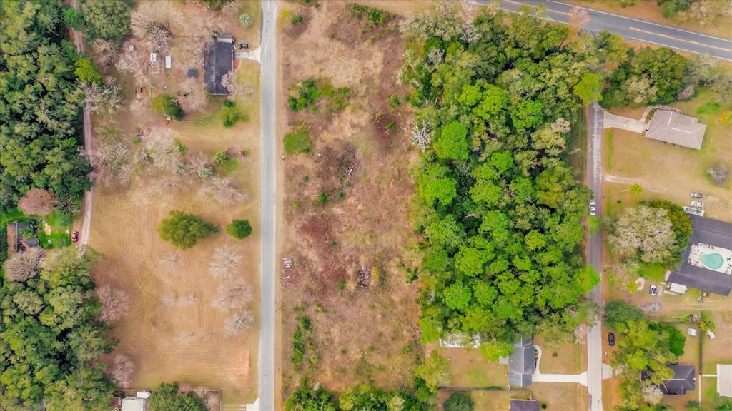 An aerial view shows a vacant, wooded lot situated between two residential streets — 3653 NE JACKSONVILLE ROAD, OCALA, FL