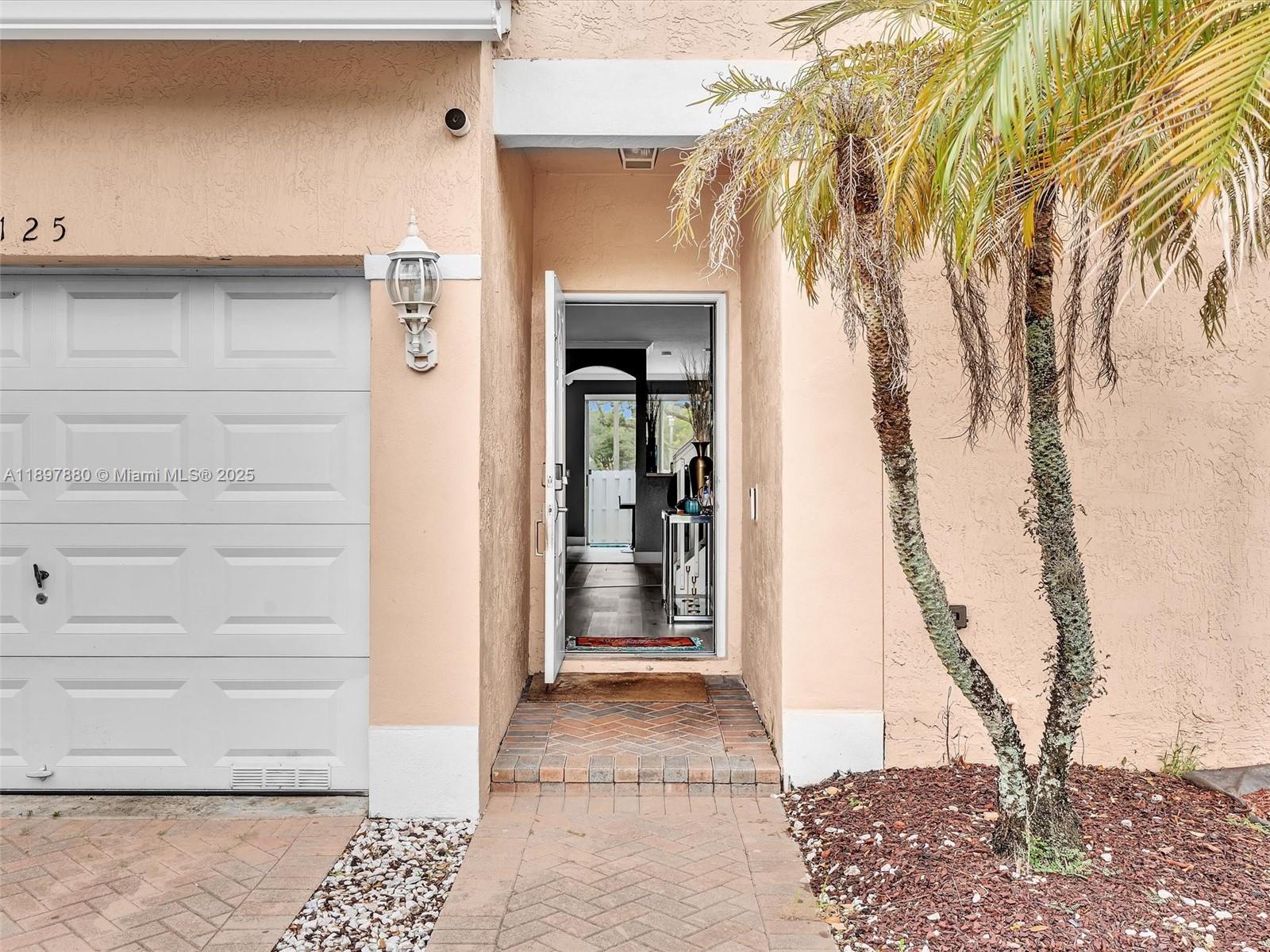 The exterior view shows a peach-colored house with a garage, front door, and palm tree — 9125 NW 40th St, Sunrise FL 33351, SUNRISE, FL
