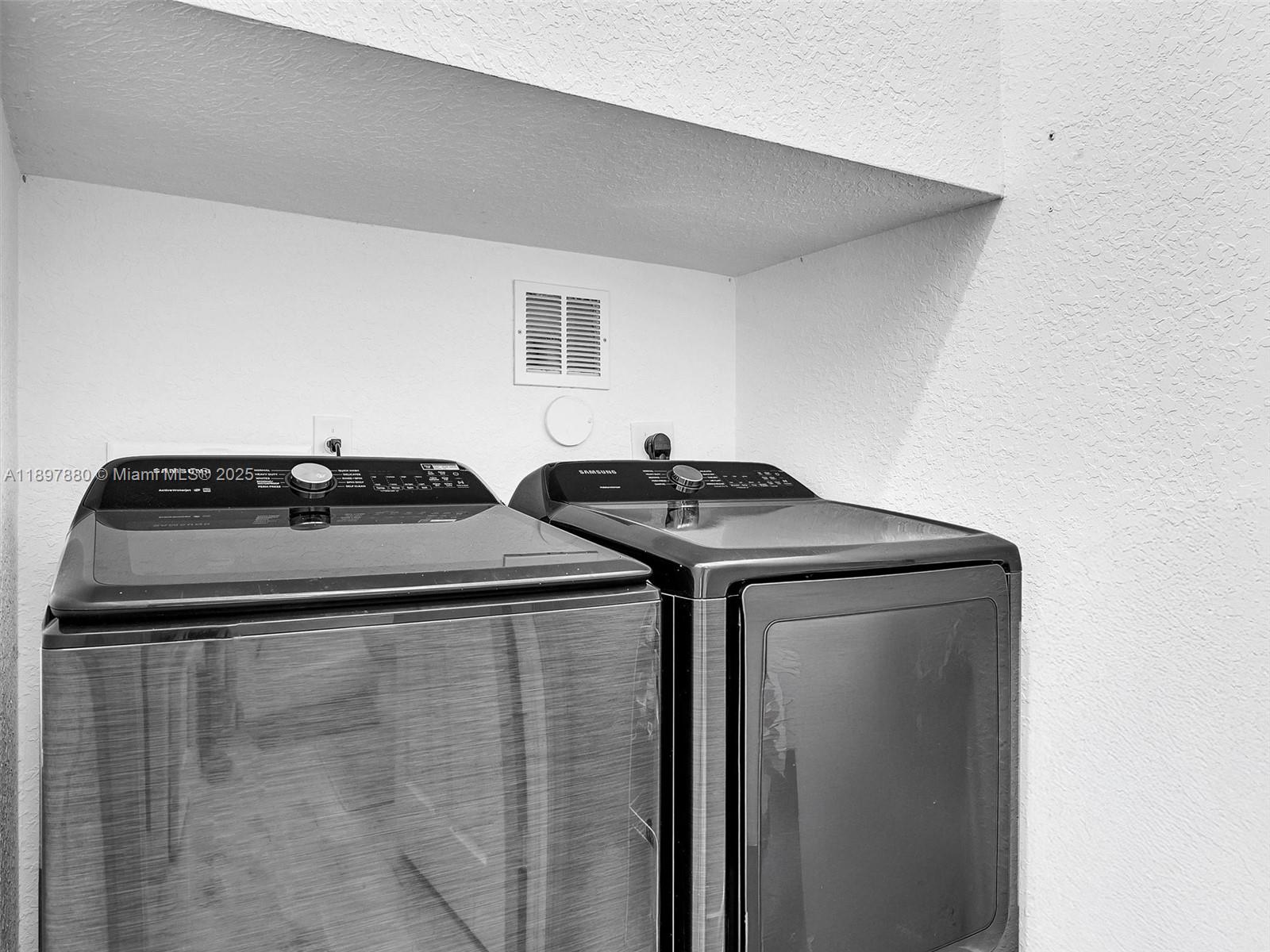 A laundry area features a black Samsung washer and dryer set against a white wall — 9125 NW 40th St, Sunrise FL 33351, SUNRISE, FL