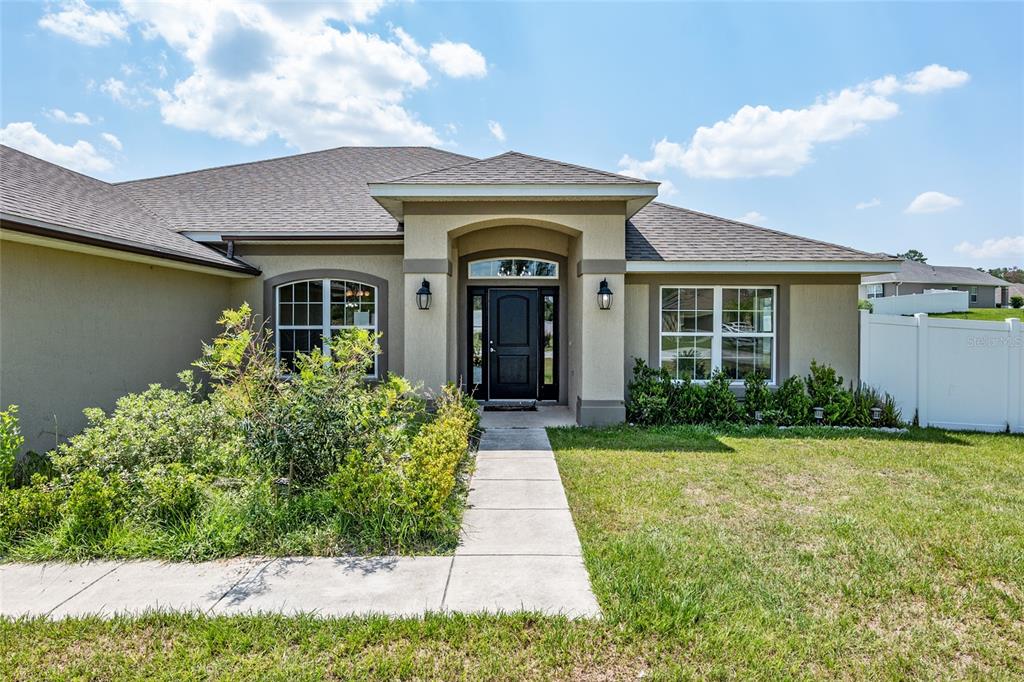 A foyer with dark wood-look tile flooring, a crystal chandelier, and a white front door — 10910 SW 41ST AVENUE, OCALA, FL