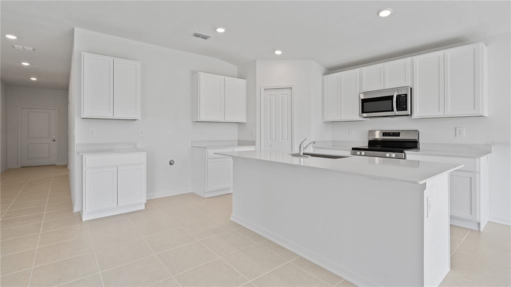 A modern kitchen features white cabinets, stainless steel appliances, and a large central island — 391 ARTEMIS STREET, LAKE WALES, FL