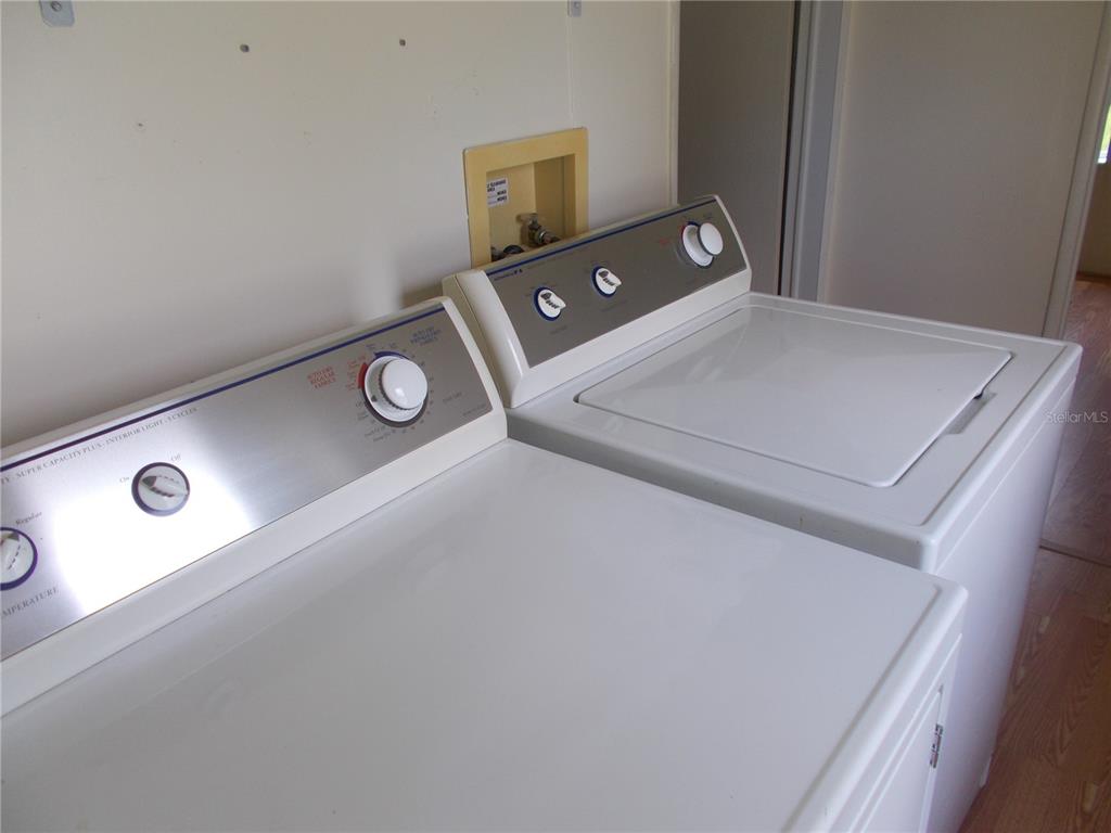 A white clothes washer and dryer sit side-by-side in a laundry room — 5787 HOLIDAY PARK BOULEVARD, NORTH PORT, FL