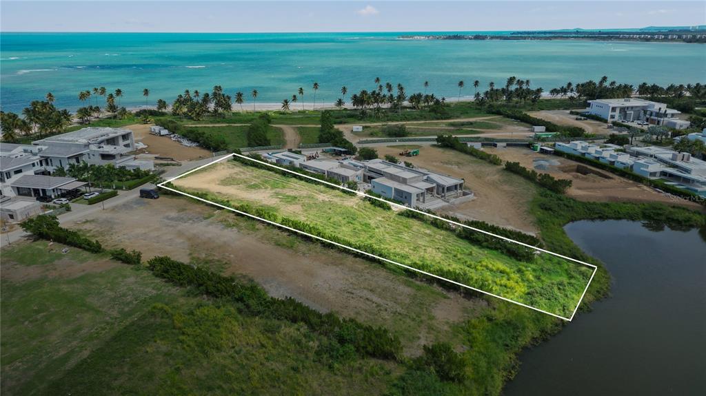 An aerial view shows a rectangular vacant lot bordered by modern houses and a pond — L5 Atlantic DR 7000 BAHIA BEACH DR, RIO GRANDE, PR