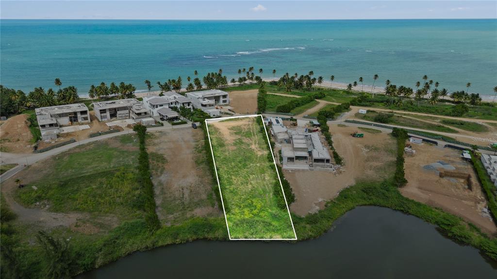 An aerial view shows a vacant rectangular lot situated between two houses near the ocean — L5 Atlantic DR 7000 BAHIA BEACH DR, RIO GRANDE, PR