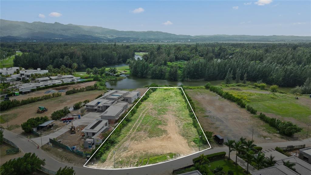 An aerial view shows a vacant, trapezoidal lot bordered by a road and a lake — L5 Atlantic DR 7000 BAHIA BEACH DR, RIO GRANDE, PR