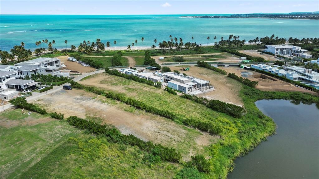 An aerial view shows a coastal development site with modern houses, vegetation, and a pond — L5 Atlantic DR 7000 BAHIA BEACH DR, RIO GRANDE, PR