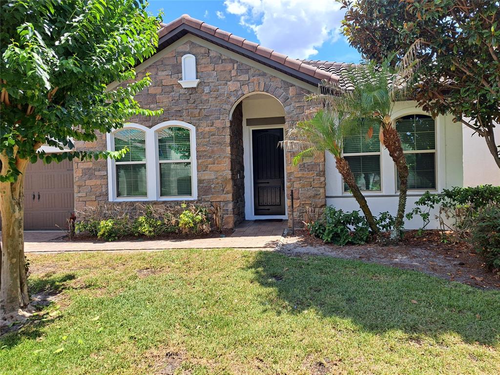 A single-story house exterior features stone veneer, a tiled roof, and a dark front door — 8420 MOREHOUSE DRIVE, ORLANDO, FL