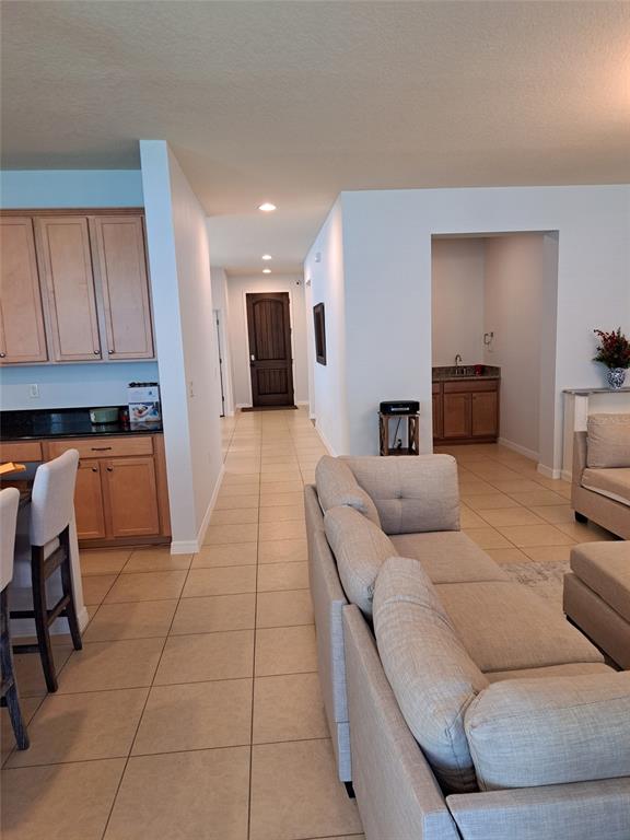 A living room with tile floors and a kitchen area leads to a hallway entrance — 8420 MOREHOUSE DRIVE, ORLANDO, FL
