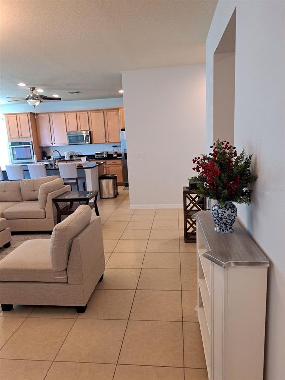 A living room with tile floors leads to an open kitchen with light wood cabinets — 8420 MOREHOUSE DRIVE, ORLANDO, FL