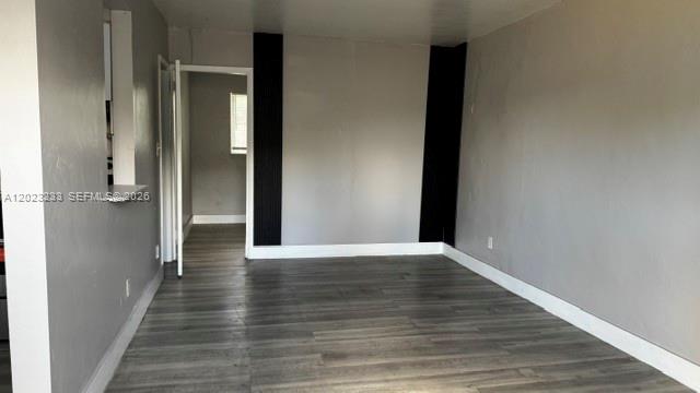 An empty room with gray walls, wood-look flooring, and a doorway leading to another area — FORT LAUDERDALE, FL