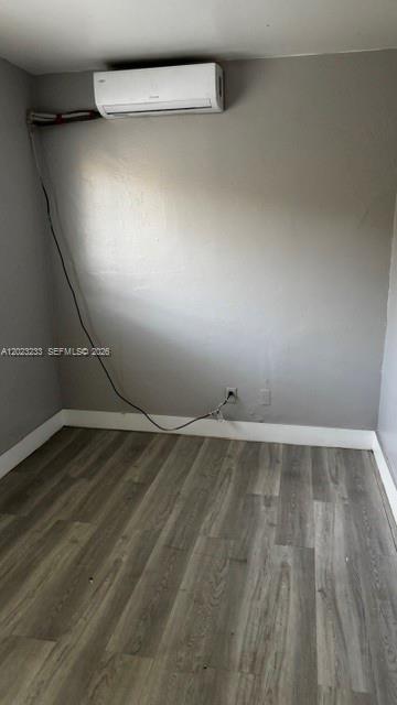 A small room with gray walls, wood-look flooring, and a wall-mounted mini-split air conditioner — FORT LAUDERDALE, FL