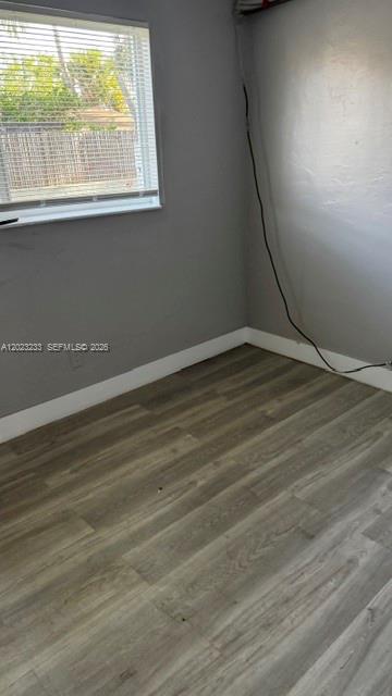 An empty room with gray walls, light wood-look flooring, and a window with white blinds — FORT LAUDERDALE, FL