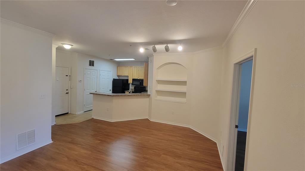 An open-concept living area features wood-look flooring, a kitchen with a breakfast bar, and shelving — 10121 COURTNEY PALMS BOULEVARD UNIT 201, TAMPA, FL