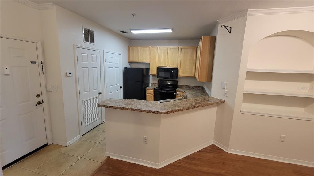 A kitchen features light wood cabinets, black appliances, and a breakfast bar with laminate countertops — 10121 COURTNEY PALMS BOULEVARD UNIT 201, TAMPA, FL