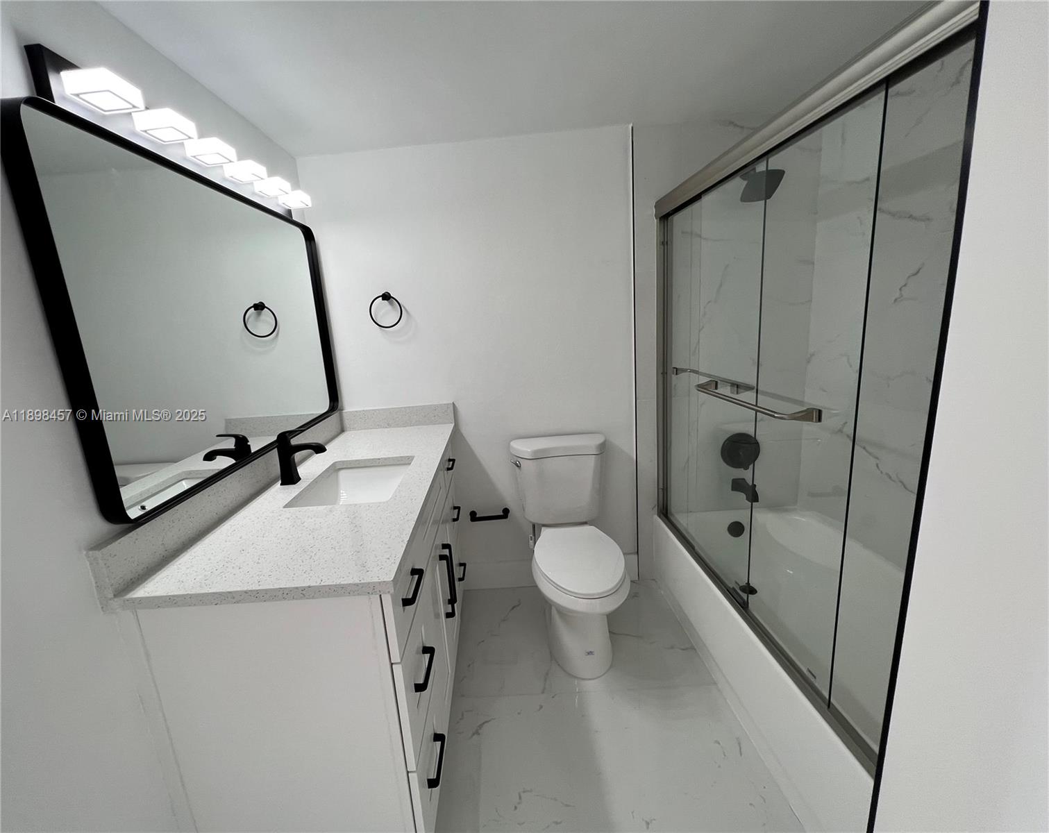 A modern bathroom features a white vanity, a black-framed mirror, and a glass-enclosed shower — 1000 West Ave # 808, Miami Beach FL 33139, MIAMI BEACH, FL