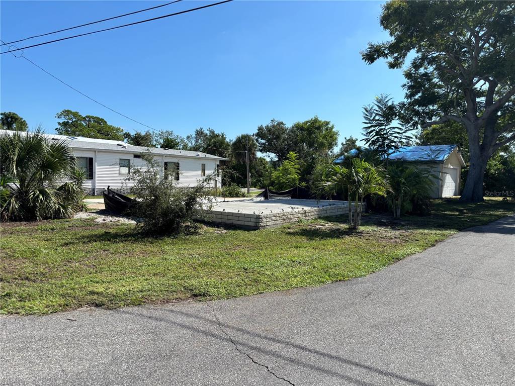 A concrete foundation sits in a grassy yard next to a house and a garage — 30 HATCHETT CREEK ROAD, VENICE, FL