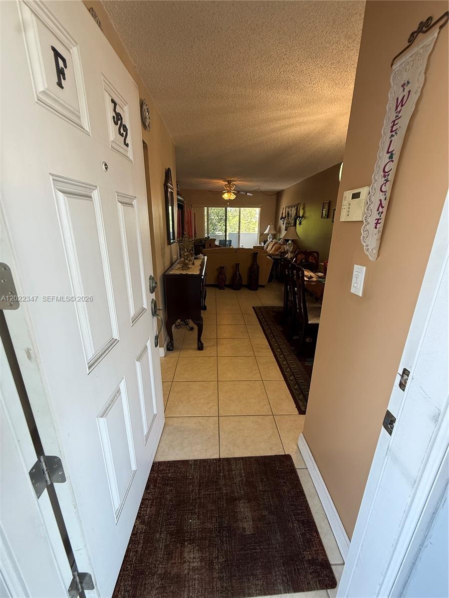 An entryway with tile flooring leads into a living room and dining area — 1725 W 60th St # F322, Hialeah FL 33012, HIALEAH, FL