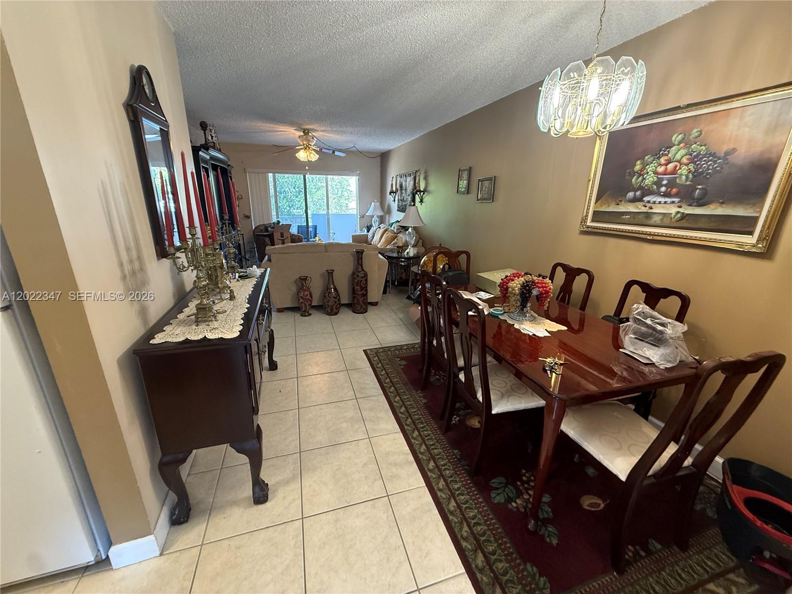 A dining area with a wooden table and chairs leads into a living room — 1725 W 60th St # F322, Hialeah FL 33012, HIALEAH, FL
