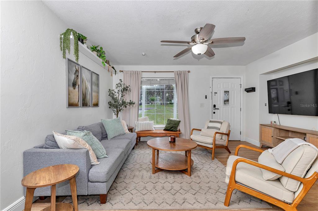 A living room features a grey sofa, two armchairs, a coffee table, and a wall-mounted television — 1302 SE SANCHEZ AVENUE, OCALA, FL