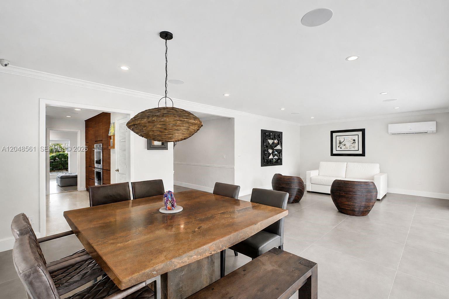 A dining area with a wooden table and pendant light opens into a living room — 2220 NE 204th St, Miami FL 33180, MIAMI, FL