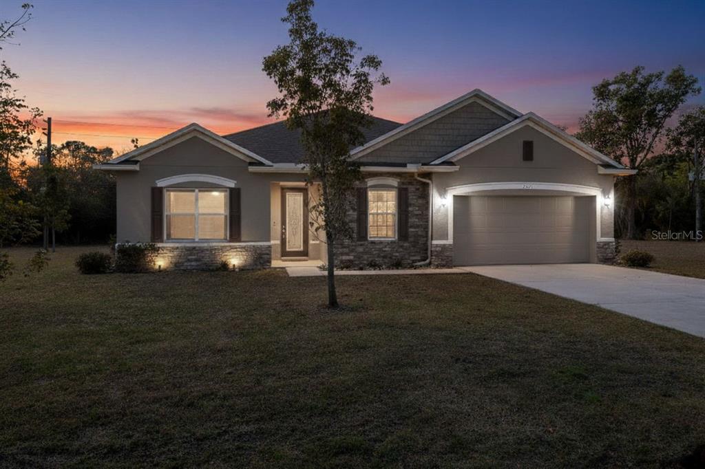 A single-story house with a tan stucco exterior, stone accents, and an attached two-car garage — 25171 DOREDO DRIVE, PUNTA GORDA, FL