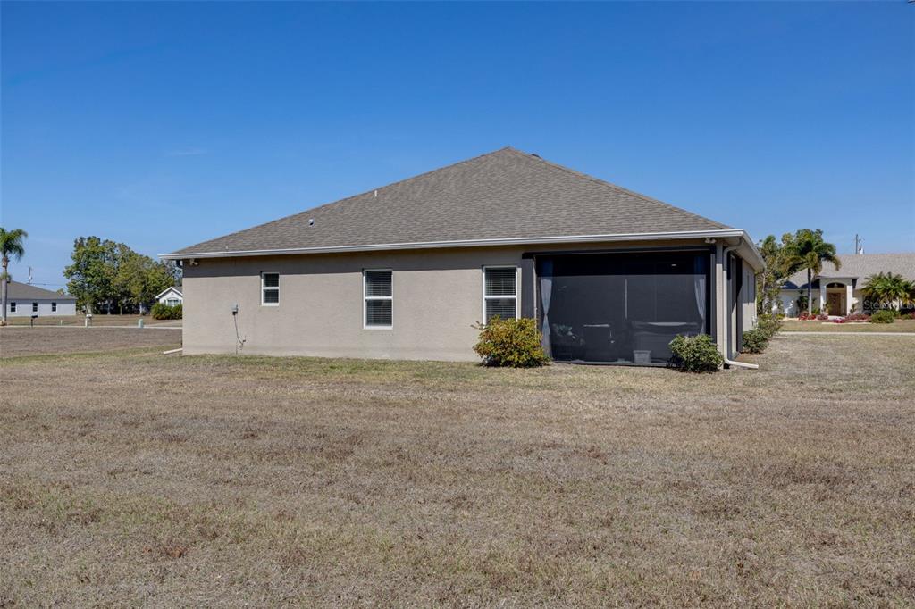 A single-story suburban house with a stone facade, a two-car garage, and a sunset sky — 25171 DOREDO DRIVE, PUNTA GORDA, FL