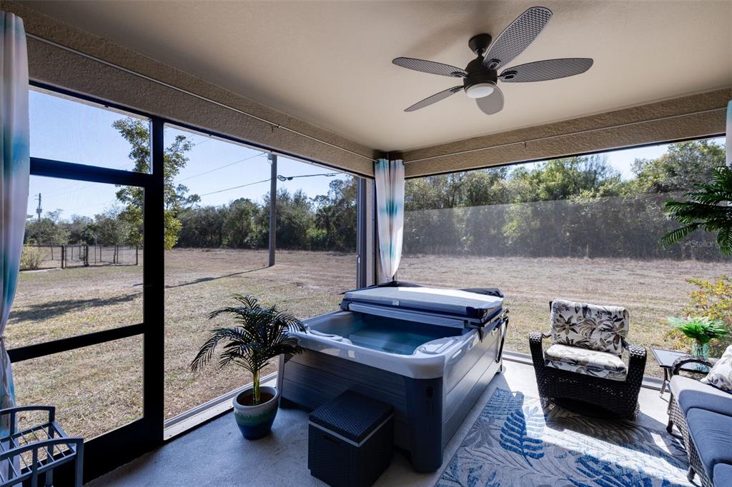 The exterior rear view of a single-story house features a screened-in patio and lawn — 25171 DOREDO DRIVE, PUNTA GORDA, FL
