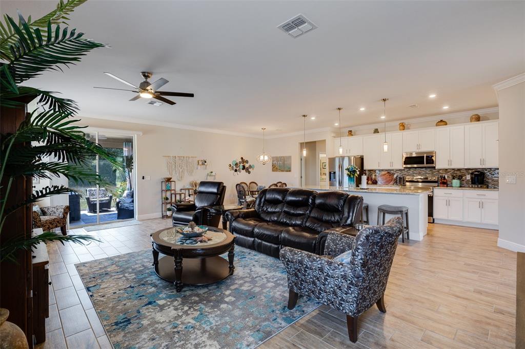 A screened-in patio features a hot tub, wicker furniture, and a ceiling fan overlooking fields — 25171 DOREDO DRIVE, PUNTA GORDA, FL