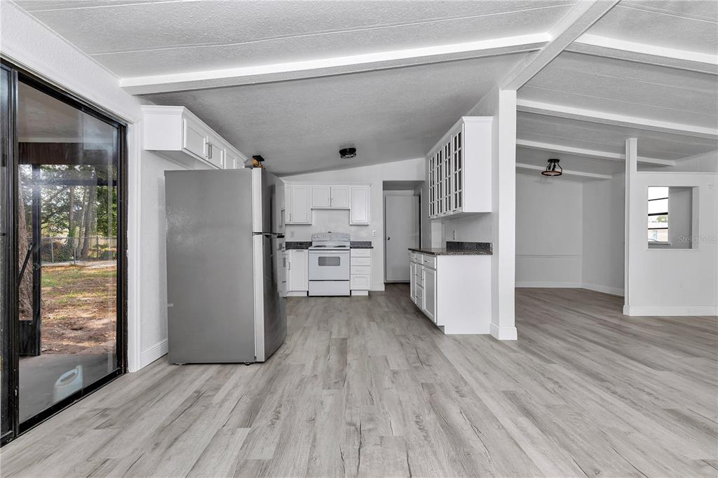 A kitchen with white cabinets, stainless steel refrigerator, and light wood-look flooring — 6741 SW 84TH STREET, OCALA, FL