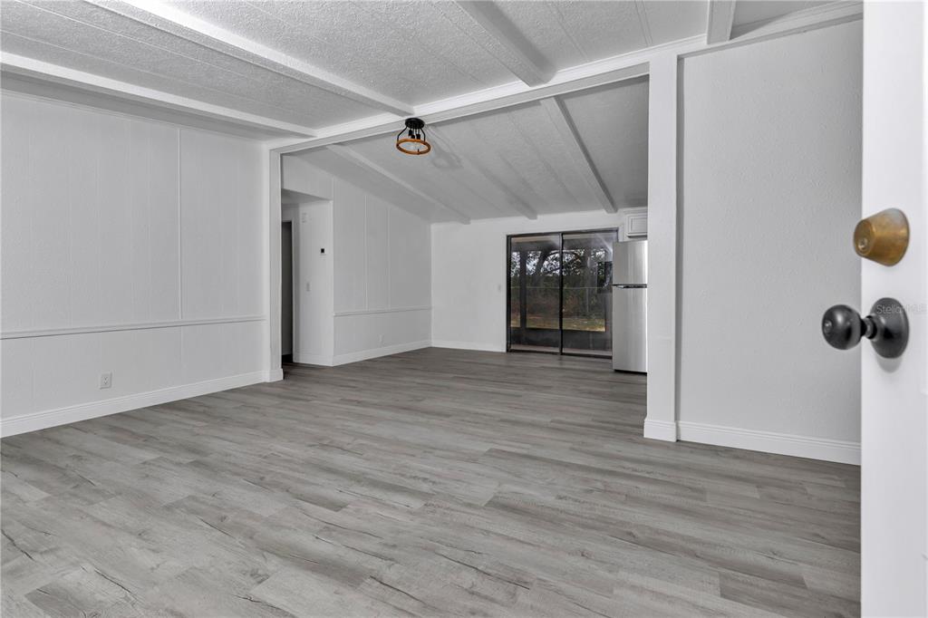 A bright, open-concept living area features white walls, wood-look flooring, and a sliding glass door — 6741 SW 84TH STREET, OCALA, FL