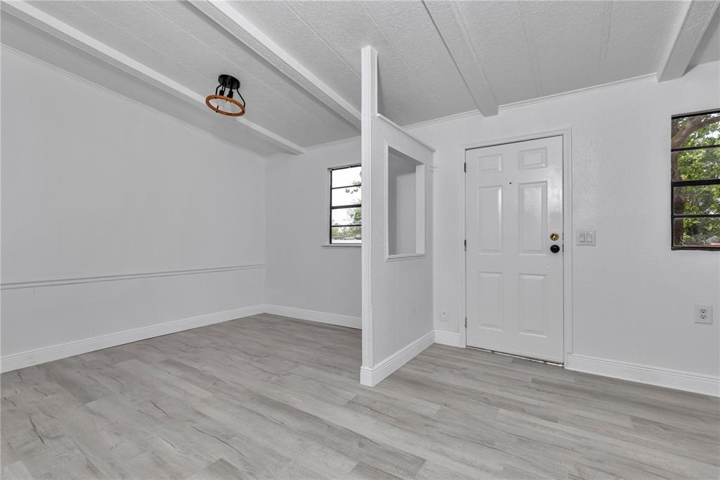 A room with white walls, light wood-look flooring, a ceiling light, and a partial divider wall — 6741 SW 84TH STREET, OCALA, FL