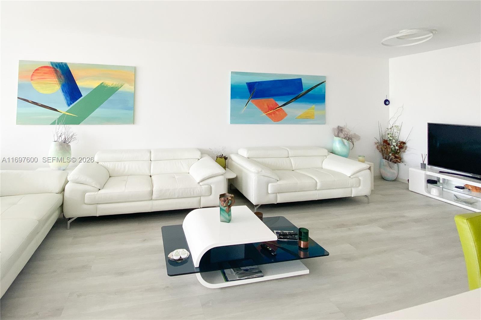 A living room features white leather sofas, a modern coffee table, and abstract wall art — 800 Parkview Dr # 708, Hallandale Beach FL 33009, HALLANDALE BEACH, FL