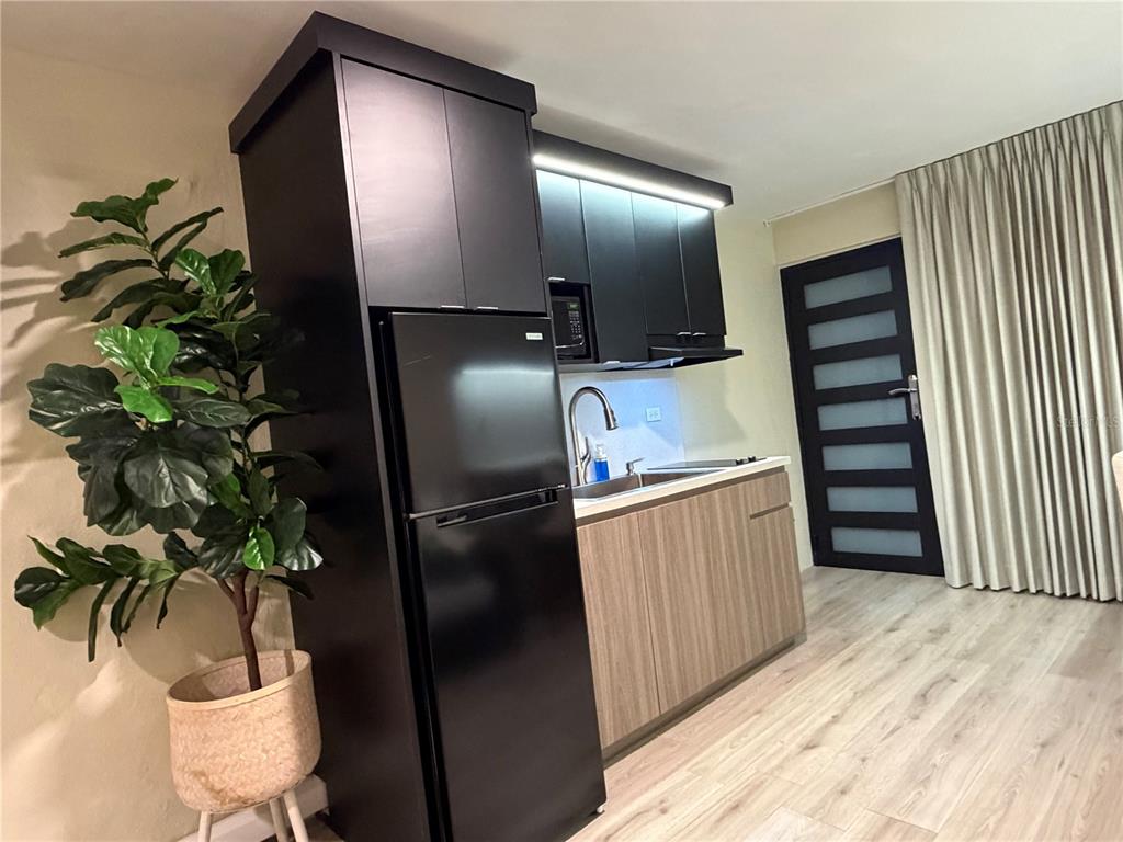 A small kitchen features black cabinets, a black refrigerator, and light wood-toned lower cabinets — 84 ST.  Num 98-1 URB BRISAS DE SIERRA BAYAMON APT. #4, BAYAMON, PR