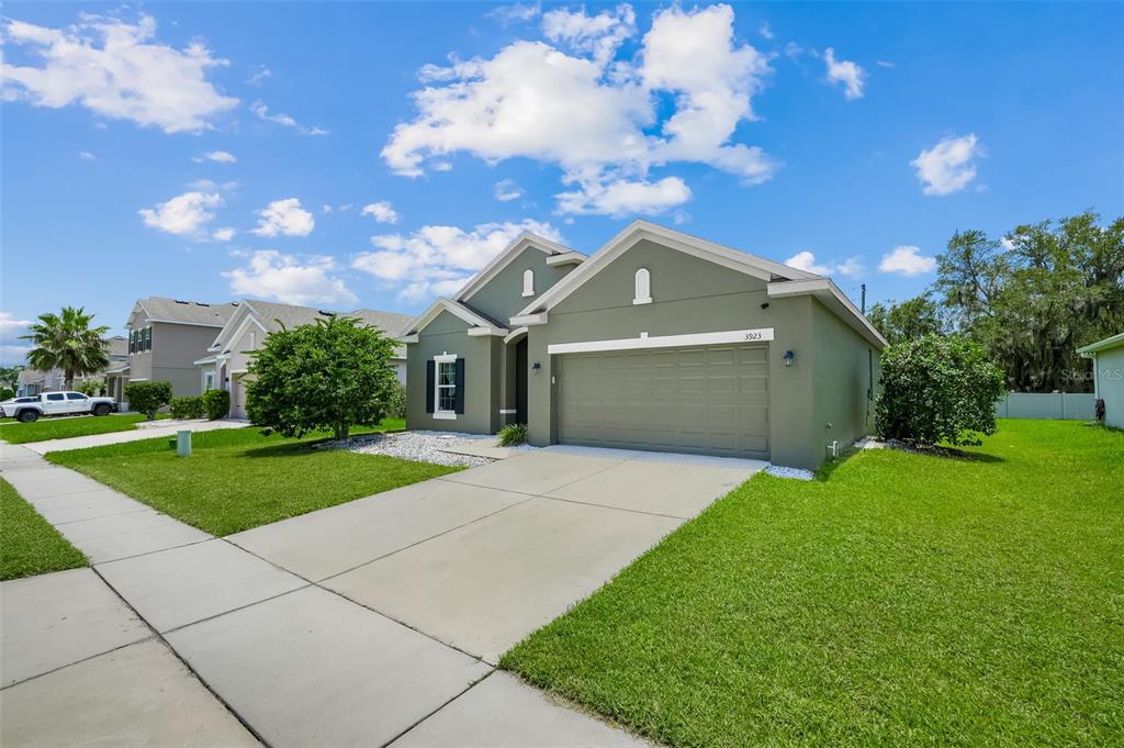 A single-story house with a green exterior, a two-car garage, and a concrete driveway — 3923 WIND DANCER CIRCLE, ST CLOUD, FL
