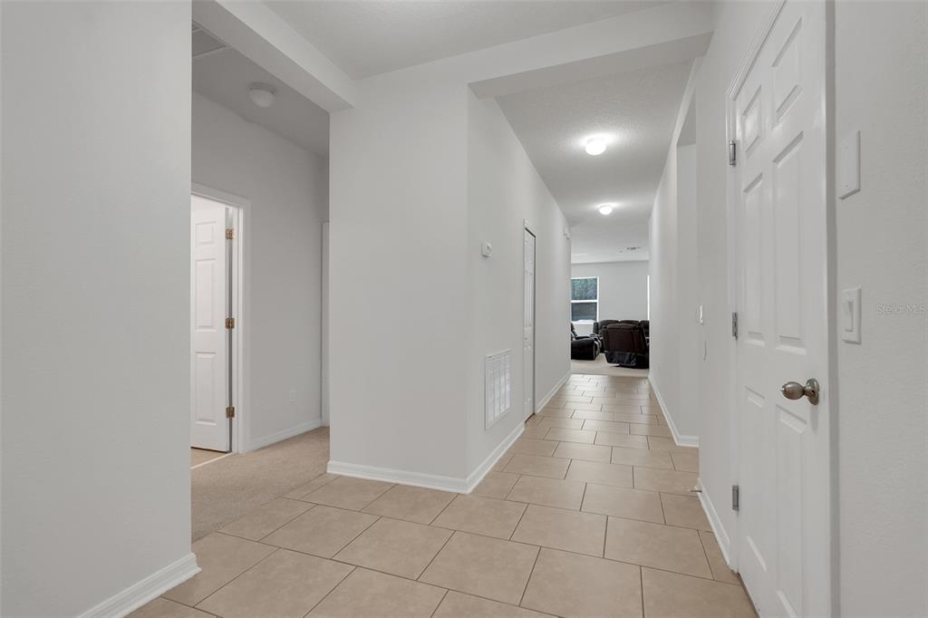 A bright hallway with light-colored tile flooring leads toward a living area in the distance — 3923 WIND DANCER CIRCLE, ST CLOUD, FL