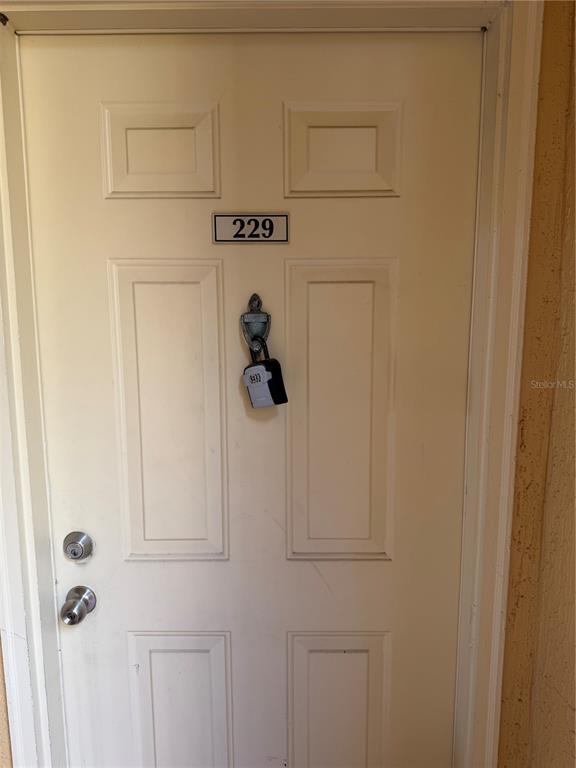 A white door with a number 229 sign and a hanging lockbox — 4333 BAYSIDE VILLAGE DRIVE UNIT 229, TAMPA, FL